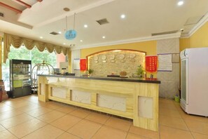 Zona de recepció amb mostrador de fusta, nevera i vitrina de vidre.