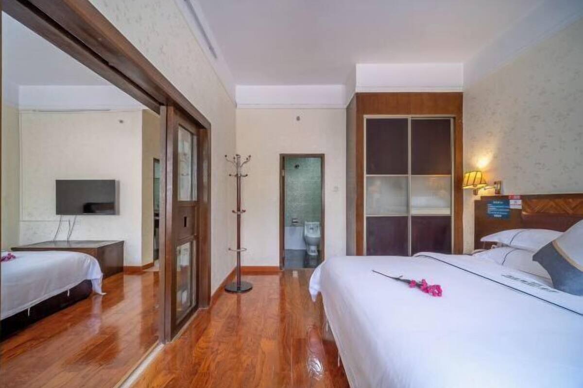 Ein Hotelzimmer mit Bett, Schreibtisch, Fernseher, Kleiderhaken und einer Badezimmertür.