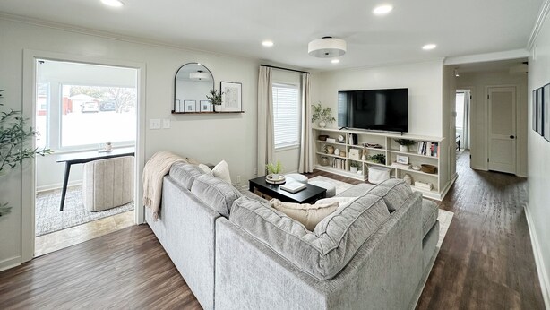 A modern living room with a grey sofa, a flat-screen TV, and a bookshelf.