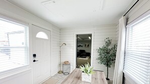 A dining area with a wooden table, a potted plant, and a view into the living room.