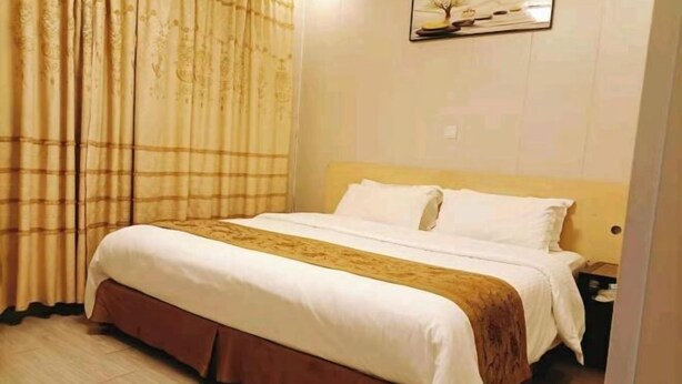 A hotel room with a bed, a nightstand, and a wall-mounted picture.