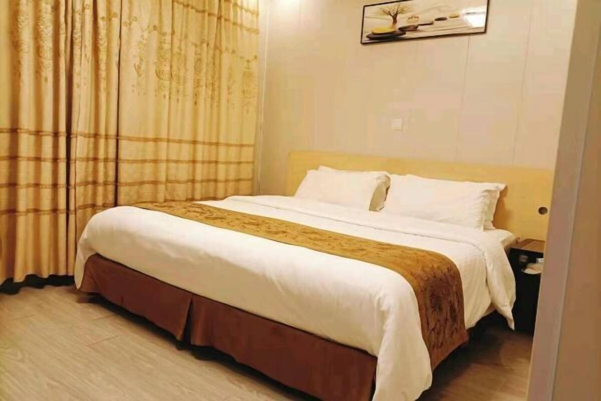 A hotel room with a bed, a nightstand, and a wall-mounted picture.