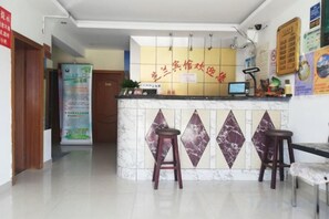 Una zona d'accés amb un mostrador de marbre, dues banquetes, un ordinador i un panell informatiu fixat a la paret.