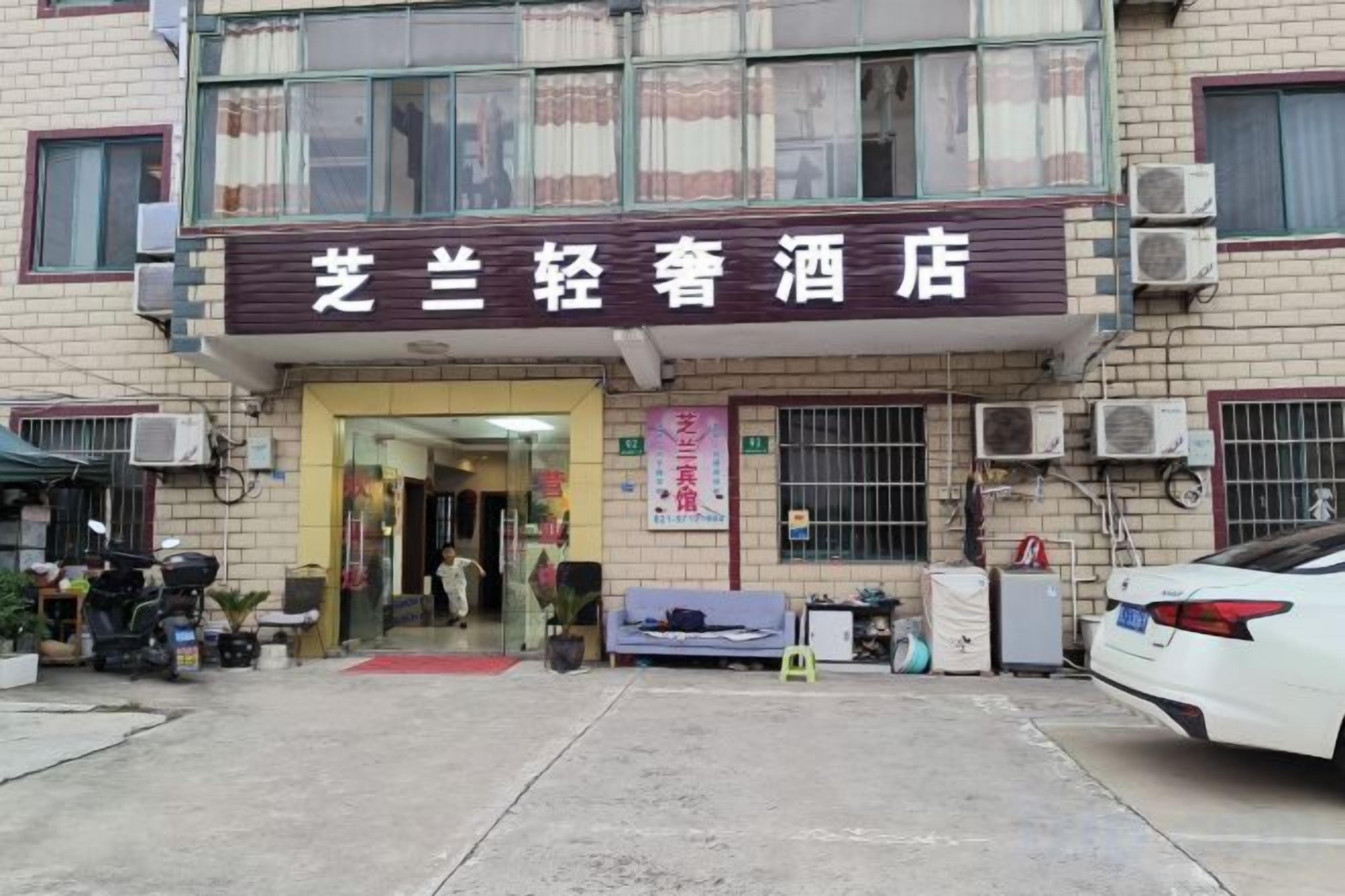 A building with a sign that reads '芒兰轻肠酒店' (Hunan Light Stomach Hotel).