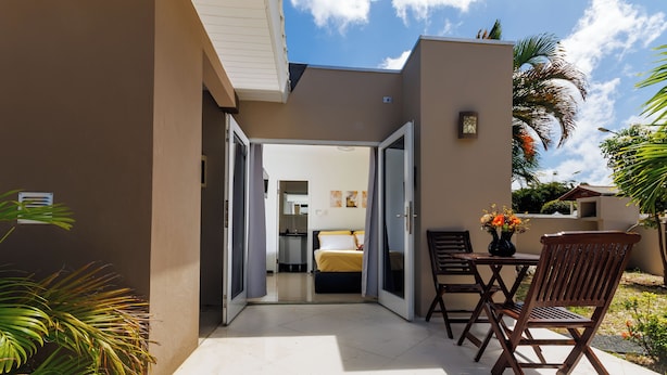 A patio area with a bed, a table, and a chair. - Las Palmeras Apartments (Willemstad)