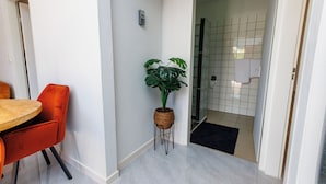 A modern kitchen with a wooden table and orange chairs, a potted plant, and a tiled backsplash. - Las Palmeras Apartments (Willemstad)
