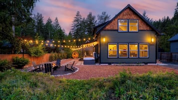 A two-story house with a stone roof, a deck, and string lights.