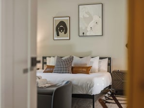 A neatly arranged bedroom with a bed, bedside tables, and two framed artworks on the wall.