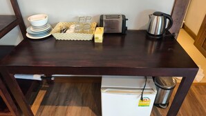 A dark wooden table with a white refrigerator, a toaster, a kettle, and a basket of items. - Cashewnut Cove Bungalow - Beach Front (Ko Lipe)