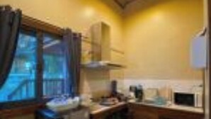 A compact kitchen with wooden cabinets, a refrigerator, and a microwave. - Cashewnut Cove Bungalow - Beach Front (Ko Lipe)
