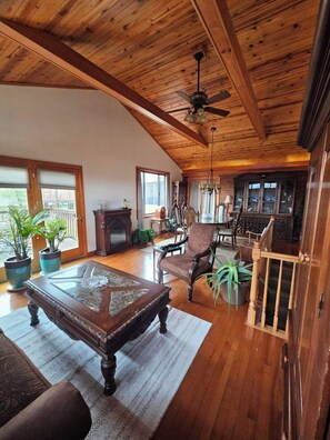 Een ruime woonkamer met houten balkenplafond, een grote houten tafel en een gezellige zithoek.