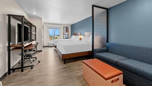 Una habitación de hotel con cama, escritorio, sillón, sofá y una pequeña mesa.