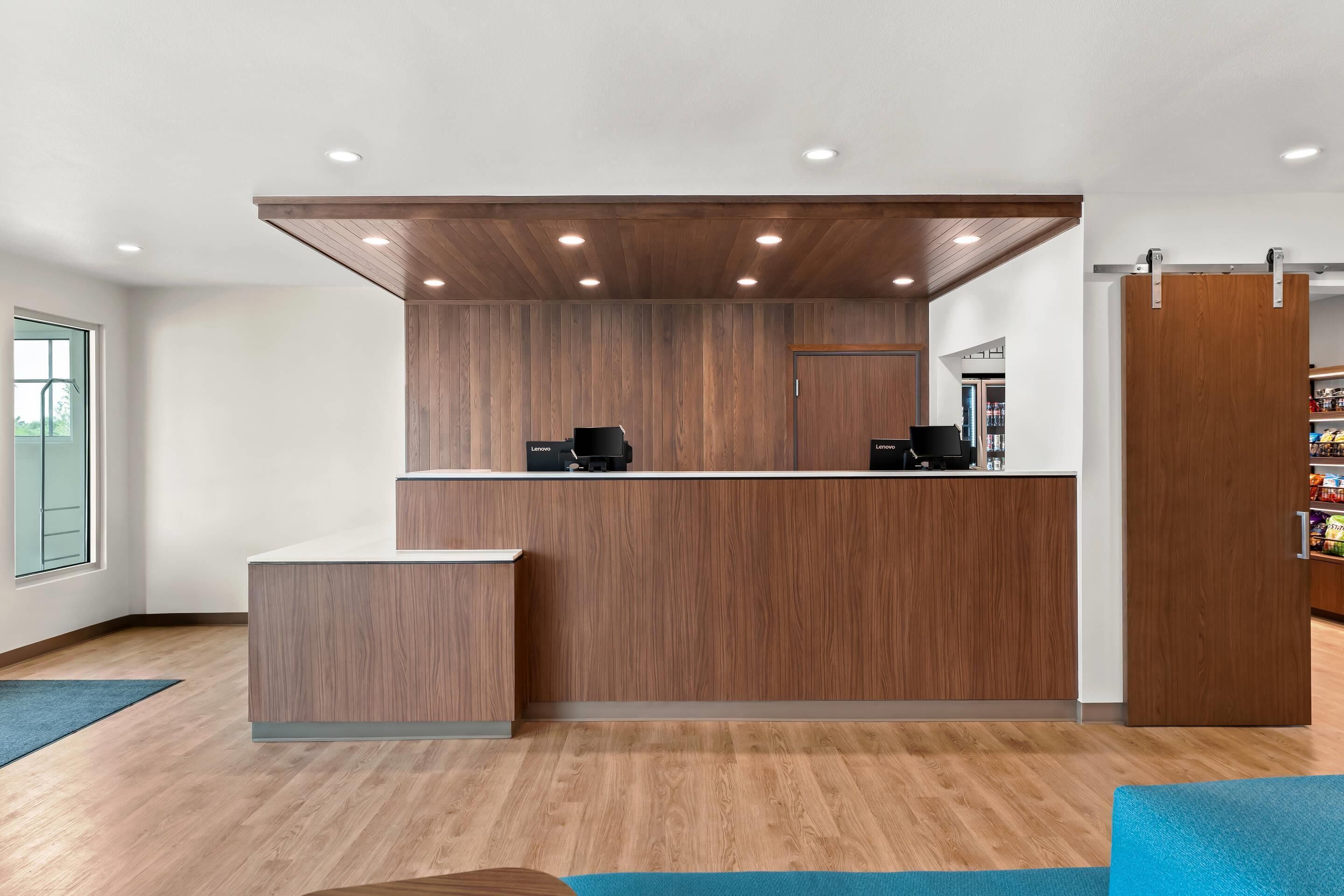 Zona de recepción con mostrador de madera, una máquina de café y una puerta corrediza hacia un área de almacenamiento.