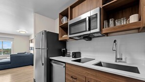 Una cocina moderna con microondas integrado, refrigerador de acero inoxidable y lavavajillas.