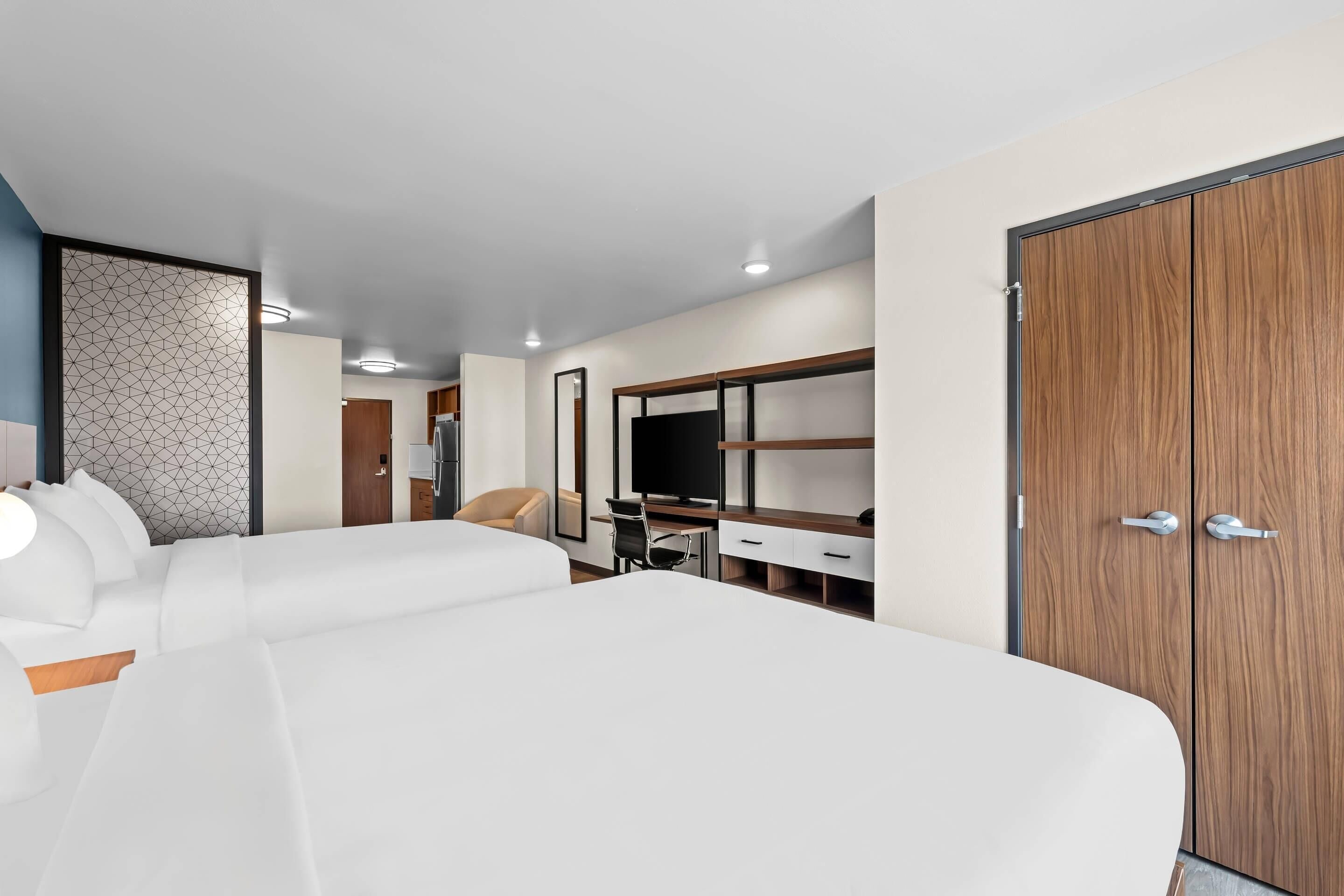 Quarto de hotel com cama grande, escrivaninha, guarda-roupa e uma cadeira.