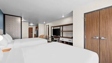 Quarto de hotel com cama grande, escrivaninha, guarda-roupa e uma cadeira.