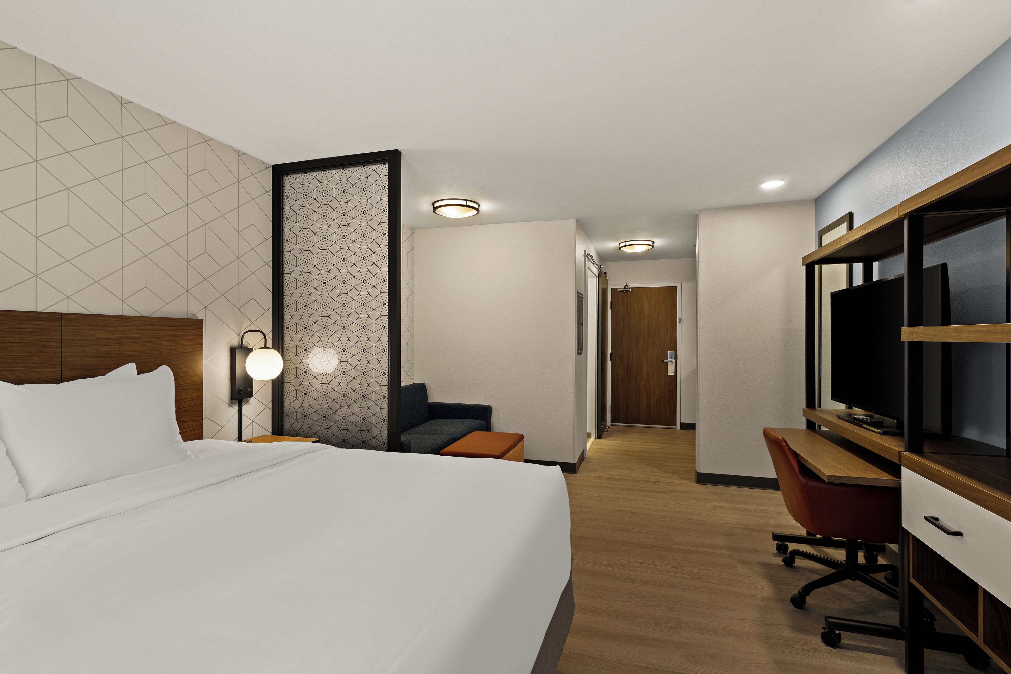 Una habitación de hotel con una cama grande, un escritorio, un televisor y una zona de estar.