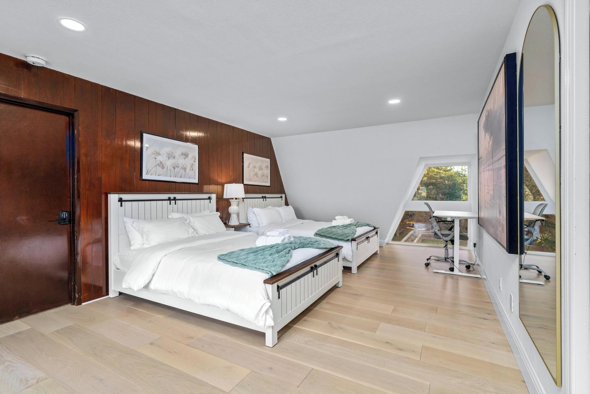 A bedroom with two beds, a desk, and a chair.