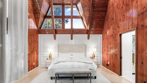 Ein geräumiges Schlafzimmer mit einem großen Bett, Holzbalkendecke und einem Oberlicht.