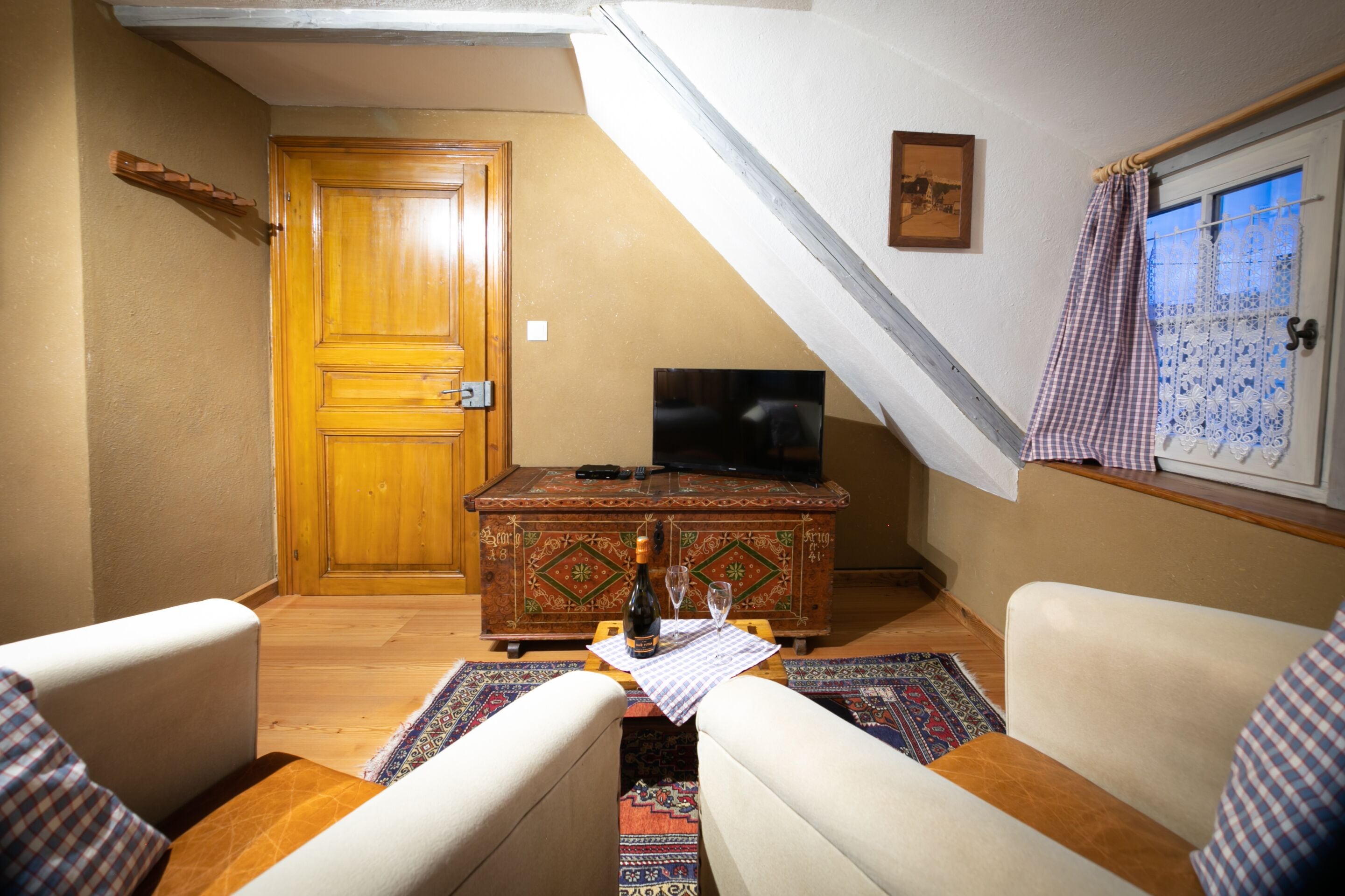 Una sala de estar acogedora con un aparador de madera, un televisor y dos sillones.