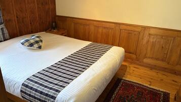 Een bed met een hartvormig kussen, een gestreept dekbed en een kamerkleed met dessin.