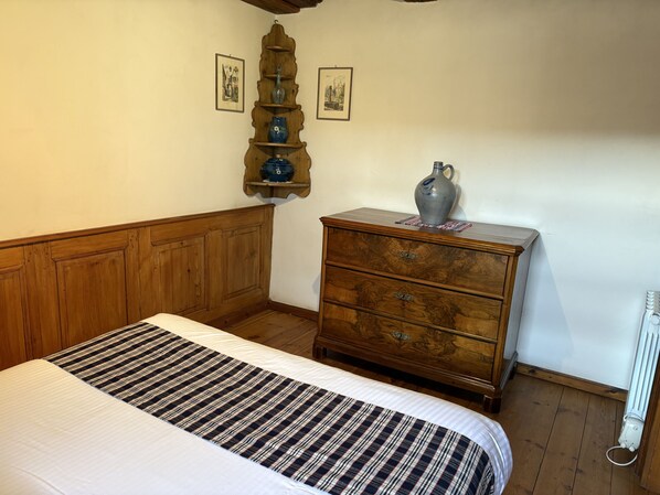 Un dormitorio con una cama de madera, un aparador y un estante en la pared con adornos.