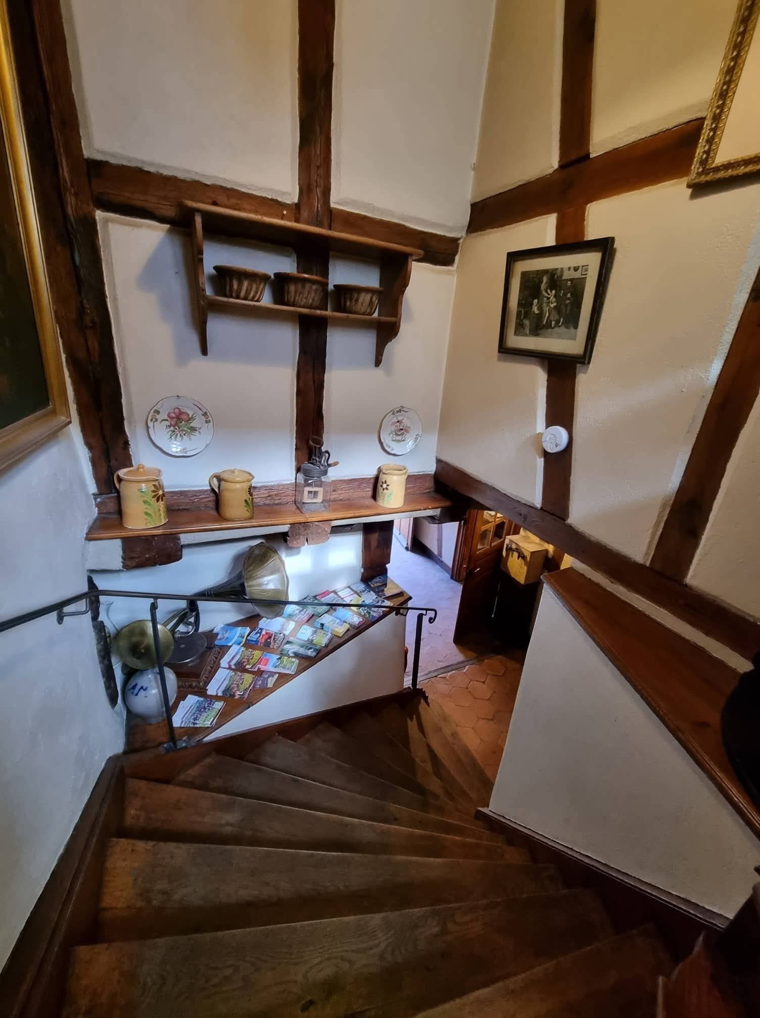 Una escalera de madera con un estante que contiene utensilios de cocina y un cuadro en la pared.