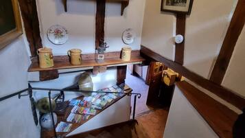 Una escalera de madera con un estante que contiene utensilios de cocina y un cuadro en la pared.