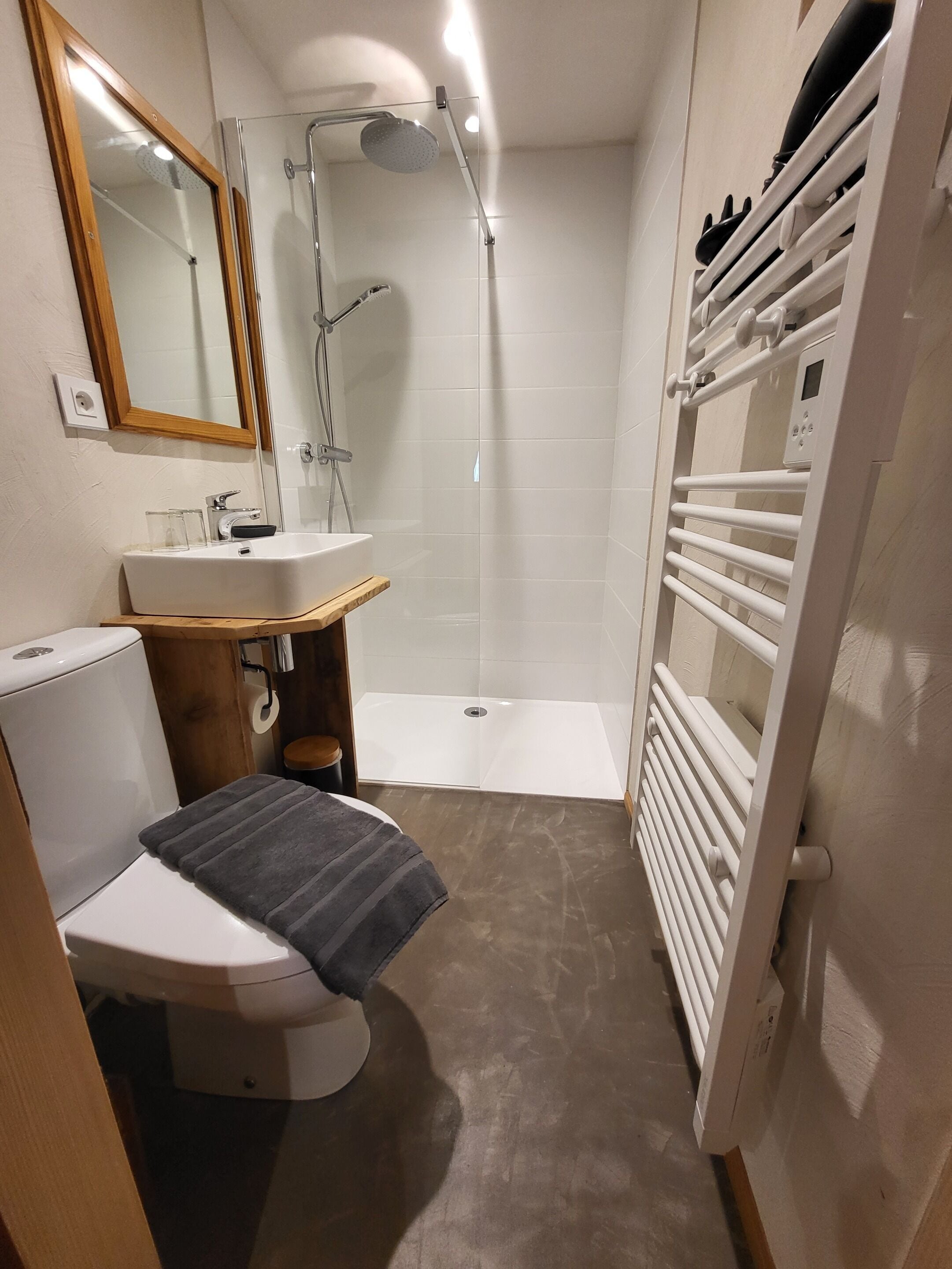 Une salle de bain compacte comprenant des toilettes, un lavabo, une douche et un porte-serviettes intégré.