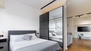 A modern bedroom with a large bed, a wardrobe with a mirror, a TV, and a wooden floor. - A terrace over St. Peter's (Roma)