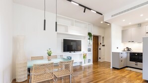 A modern kitchen with white cabinetry, a built-in oven, and a dining area with a glass table and wicker chairs. - A terrace over St. Peter's (Roma)
