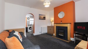 Una sala de estar moderna con sofá, chimenea, televisor y zona de lavandería.