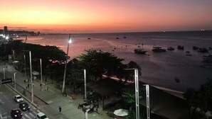 A coastal cityscape at sunset with a view of the sea, boats, and a pedestrian walkway along the waterfront. - Stunning view! Sea Front! (Mucuripe Fortaleza)