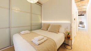 Un dormitorio moderno con una cama grande, una mesita de noche con un florero y una puerta corredera de vidrio.