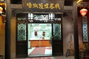 Una entrada tradicional china con un letrero, una bicicleta y un farol rojo.