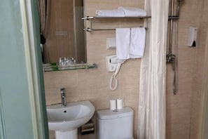 A bathroom with a sink, toilet, towel rack, and shower.