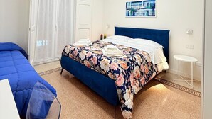 A bedroom with a bed, a small table, and a painting on the wall.