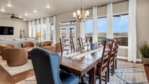 A spacious dining area with a wooden table, chairs, and a chandelier. - Pool, Sandy Beach & Amazing Lake Sunsets, Sleeps 16, Family Retreat + Game Room (Kingsland)