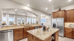 A spacious kitchen with granite countertops, wooden cabinets, a stainless steel refrigerator, and a large island. - Pool, Sandy Beach & Amazing Lake Sunsets, Sleeps 16, Family Retreat + Game Room (Kingsland)