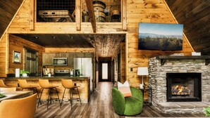 A spacious wooden cabin interior with a kitchen, dining area, and a stone fireplace.