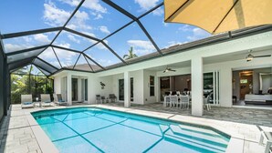 Una piscina con techo de vidrio, rodeada de sillones de descanso y un área de comedor.
