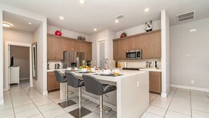 Una cocina moderna con una isla central, electrodomésticos de acero inoxidable y una zona de comedor con taburetes de bar.