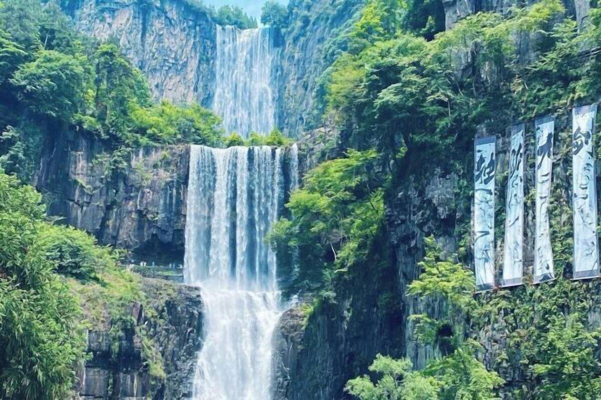 Ein Wasserfall stürzt über eine felsige Klippe, umgeben von üppigem Grün.