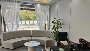 A modern room with a curved sofa, a round coffee table, a dining table with chairs, and a potted plant.