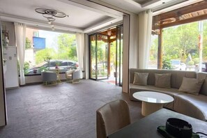 A modern living room with a sofa, coffee table, and a dining area with chairs and a small table. - Wencheng Wufu Farmhouse (Wencheng)