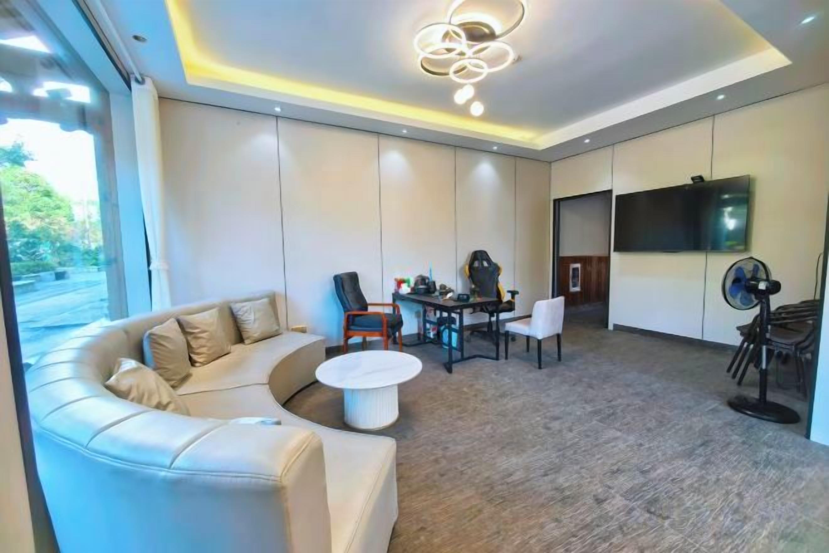 A modern living room with a sectional sofa, a round coffee table, and a dining area with chairs and a table.
