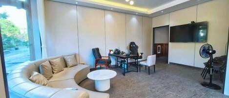 A modern living room with a sectional sofa, a round coffee table, and a dining area with chairs and a table.