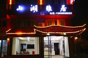 A building with a traditional Chinese architectural style, featuring a red roof and illuminated signage.