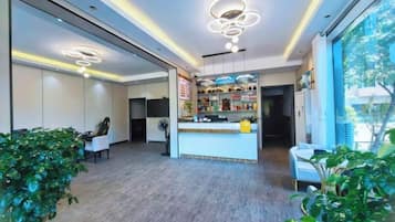 A hotel lobby with a reception desk, seating area, and large windows.