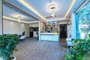 A hotel lobby with a reception desk, seating area, and large windows.